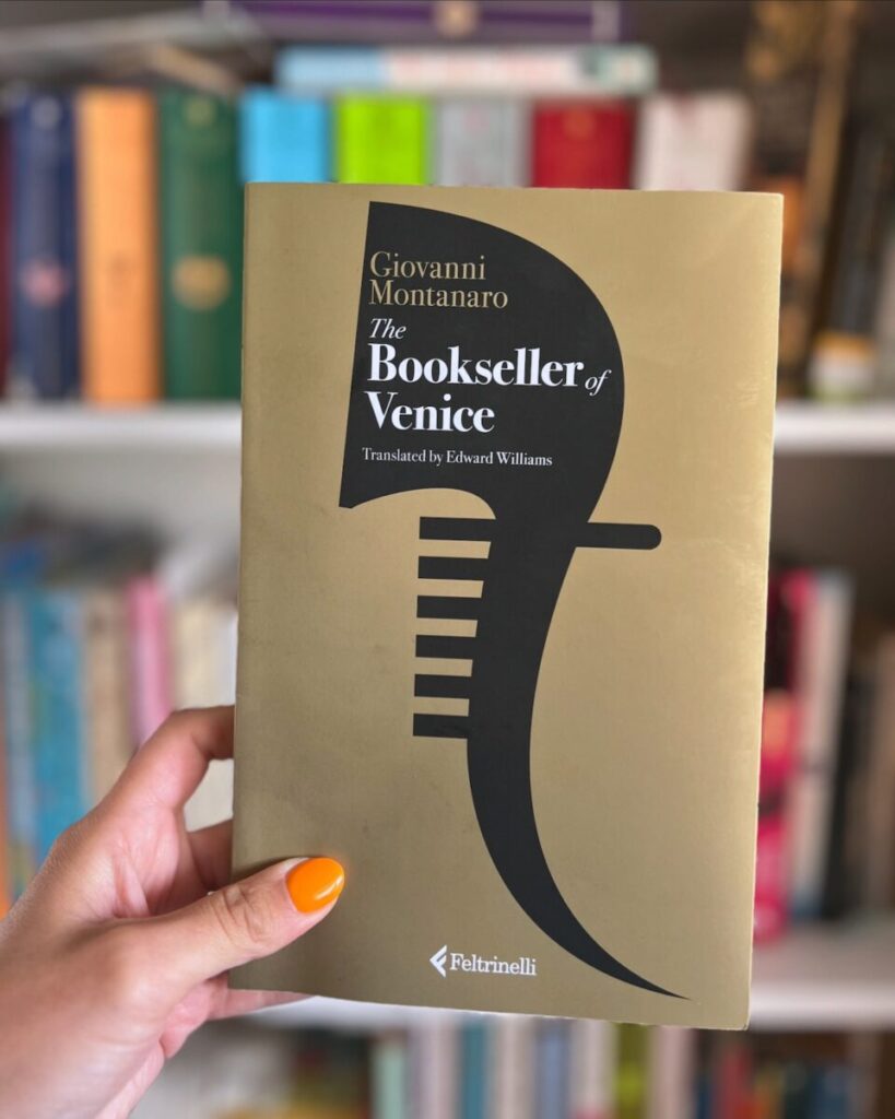 bookseller of venice book held in front of bookshelf