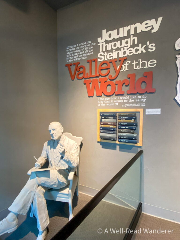 statue of john steinbeck, man seated in a chair with writing implements at national steinbeck center entry
