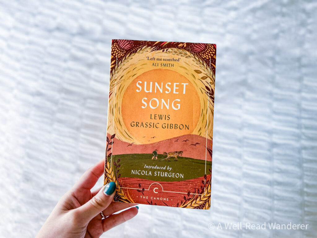 sunset song by lewis grass gibbons, sunset illustrated paperback book held in front of white background