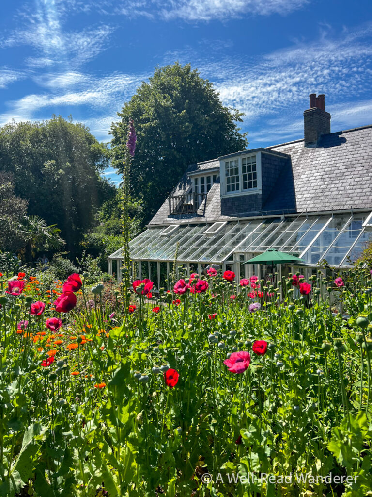monks house virginia woolf house, flower garden in forefront with house and attached greenhouse behind