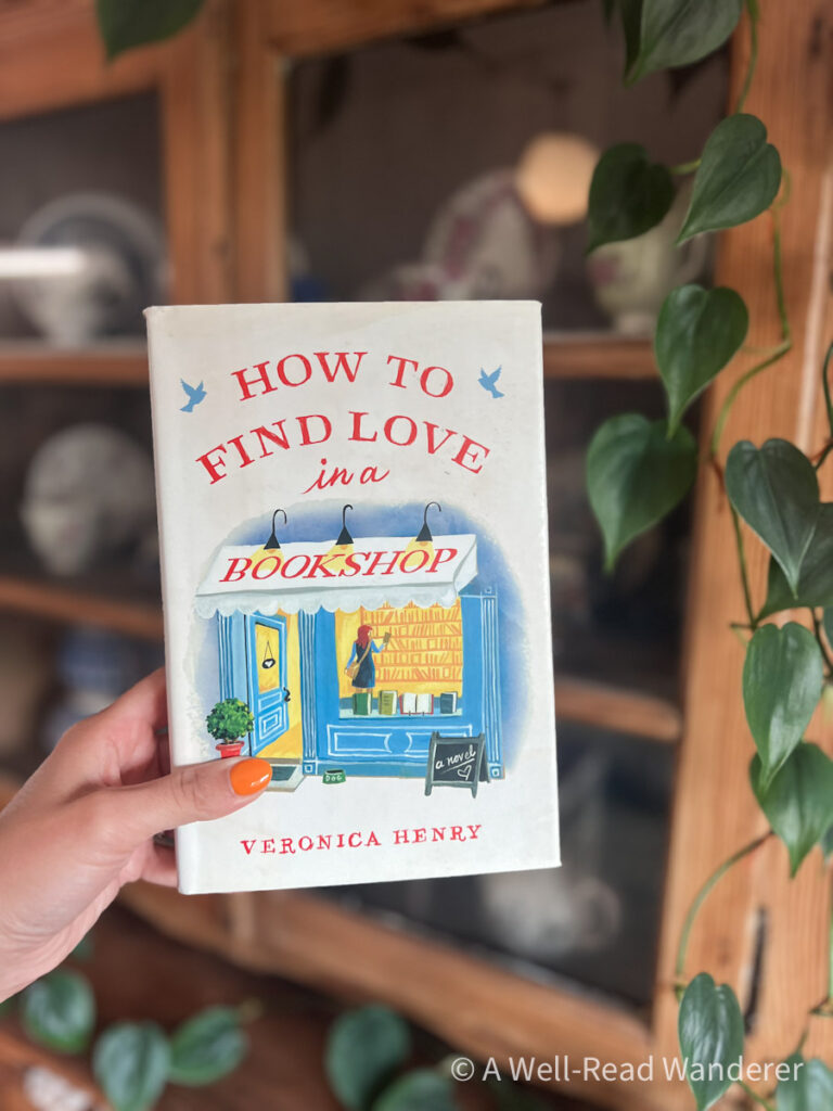 how to find love in a bookshop book held by hand in front of antique cabinet
