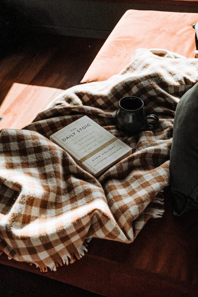 A warm, inviting reading nook featuring a book, checkered blanket, and a cozy cup of coffee.