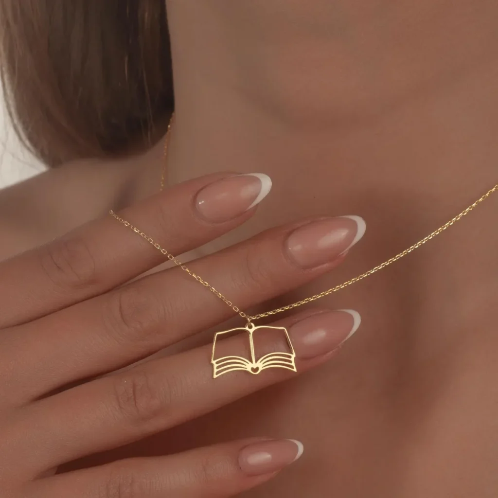woman holds gold toned book shaped necklace
