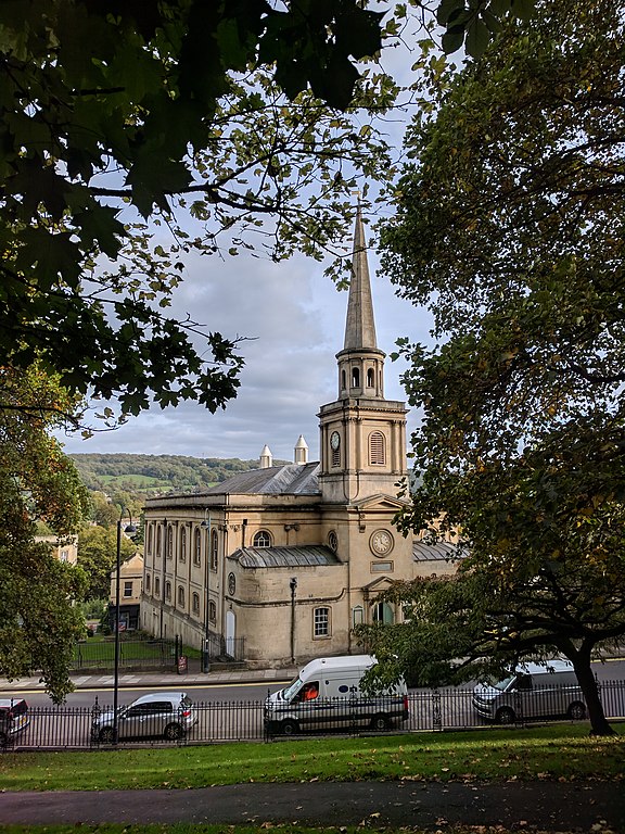 exterior of st swithins church in bath where jane austen's parents were married, trees in foreground and church spire in the distance