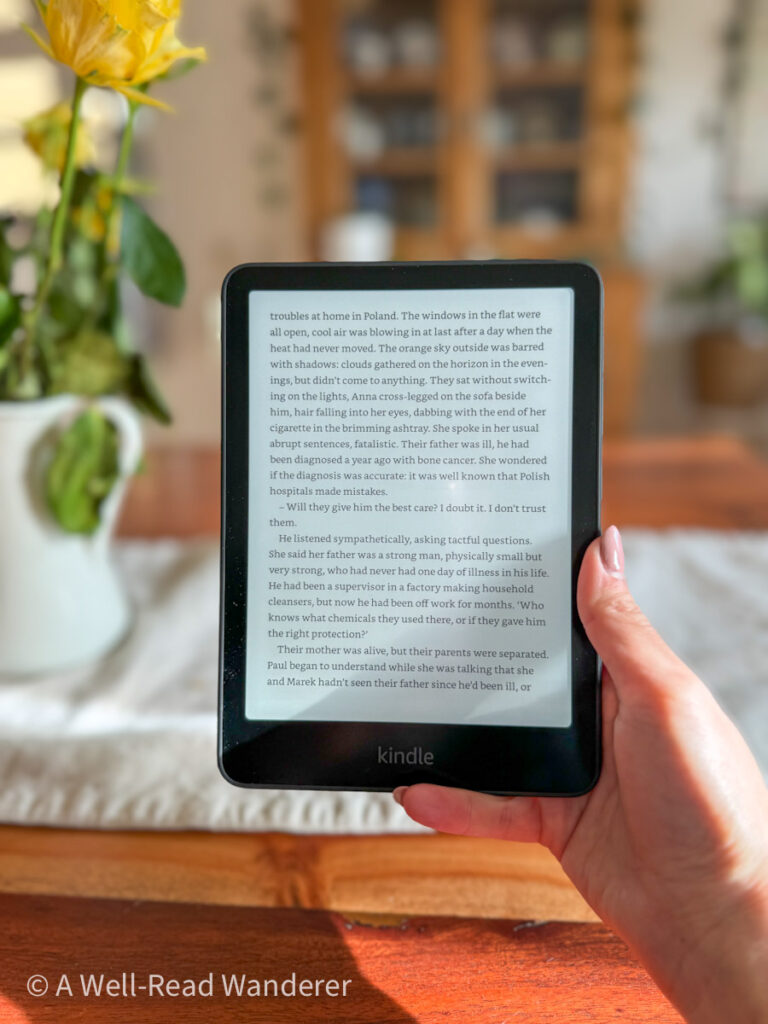 kindle paperwhite 12th generation held by hand in front of dining room table with flowers