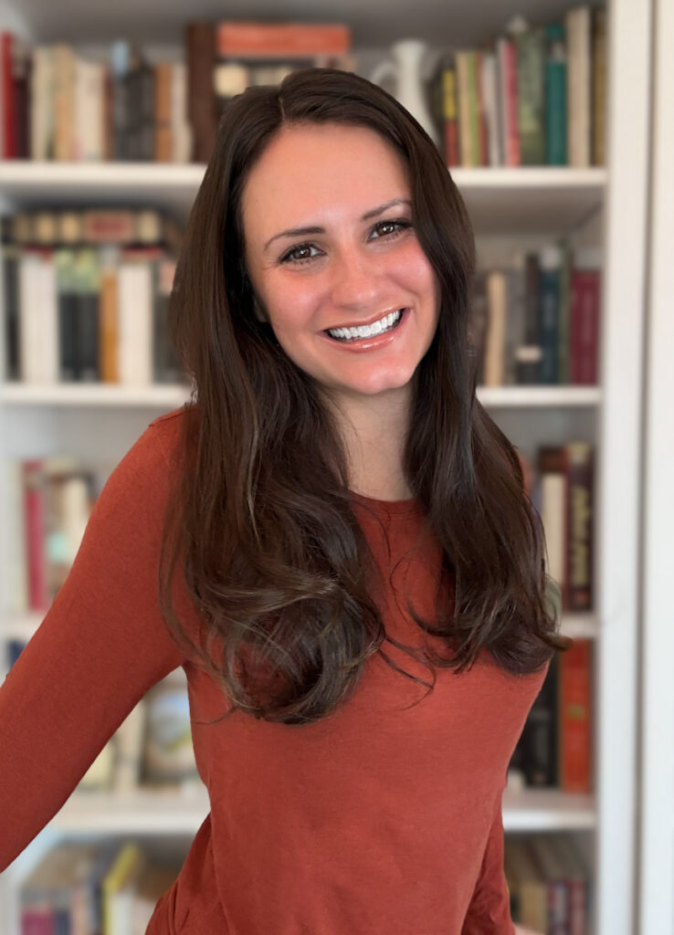 brunette woman smiling in front of bookcase constance ray author of a well-read wanderer and literary travel expert