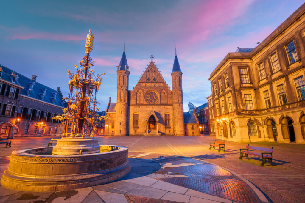 the hague city centre at sunrise with the ridderzaal historic building in background and an old fountain in foreground
