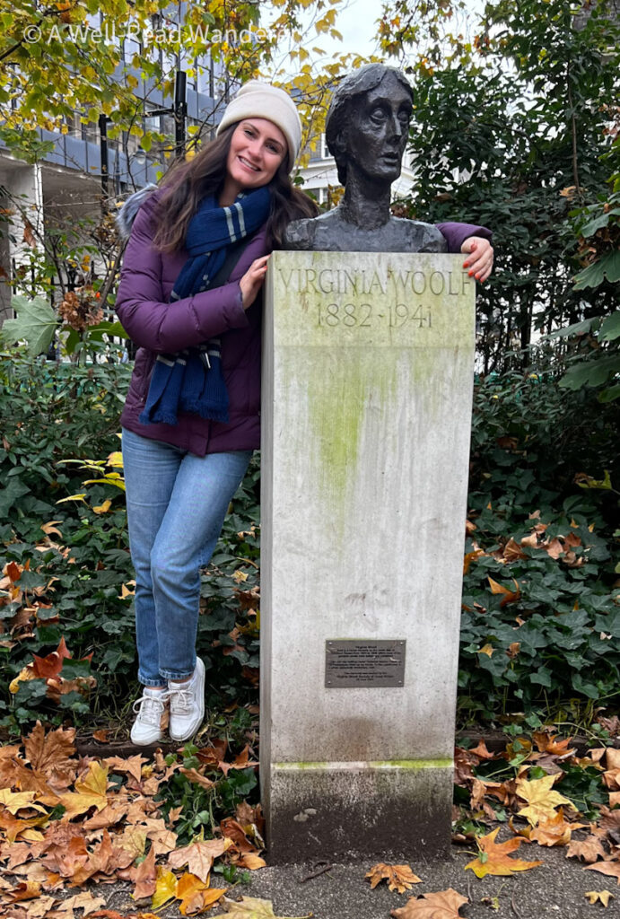 beautiful woman stands and smiles next to bust of virginia woolf in tavistock square london
